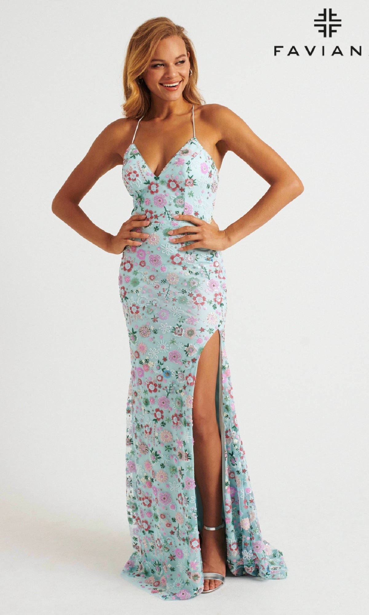 A woman stands and smiles in the Faviana 11263 light blue floral beaded long prom dress with thin straps, a fitted bodice, a thigh-high slit, and the